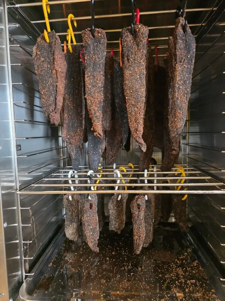 Biltong hanging on two racks inside the Kalahari Khabu KK16 Biltong Boss