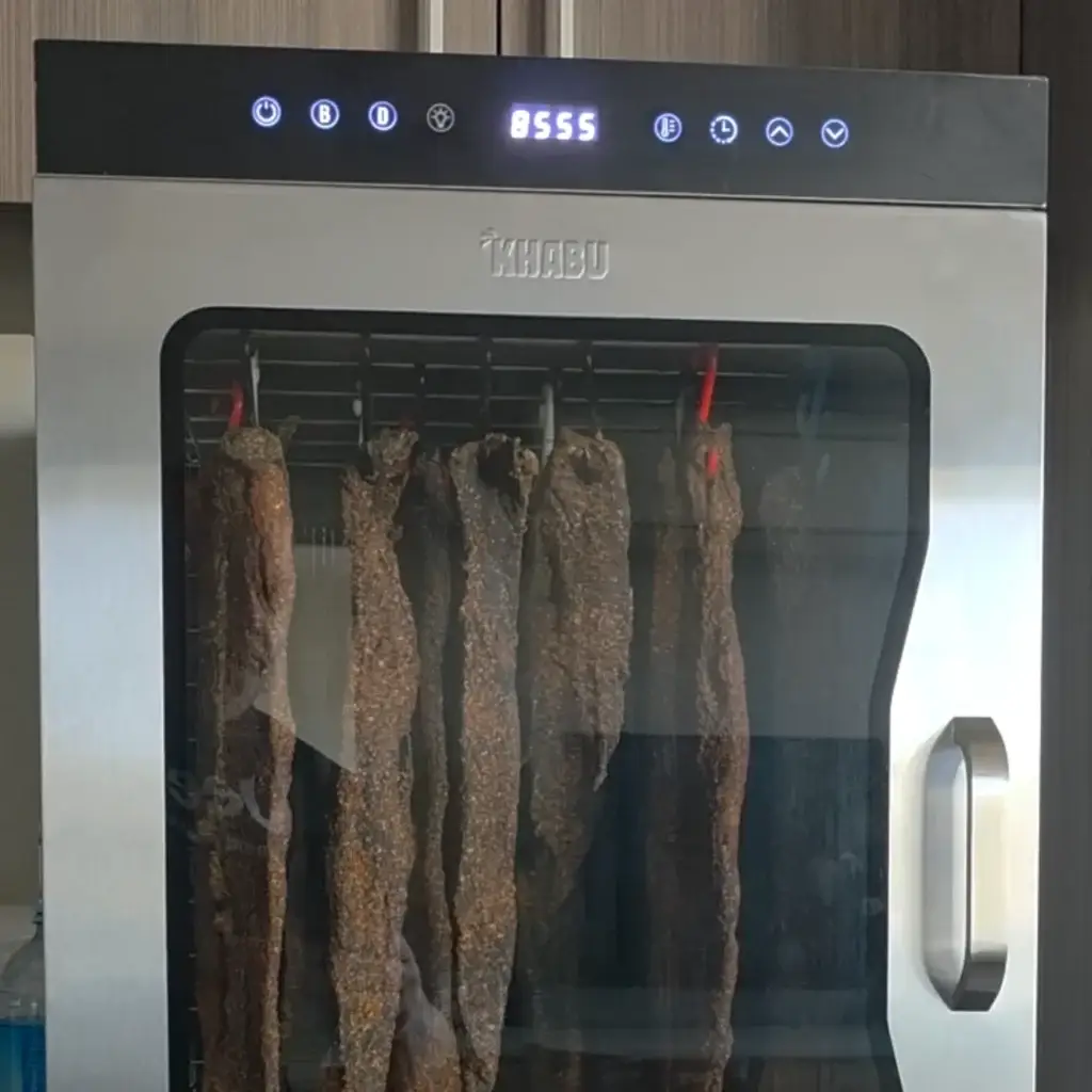 Beef biltong hanging on hooks inside the Kalahari Khabu KK12 Biltong Boss with the 96 hour timer running
